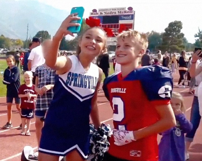 Cheerleader and football player taking a selfie, related to momfluencer abuser docuseries.