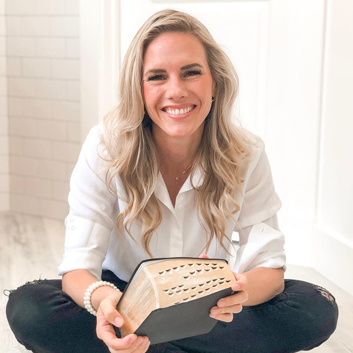 A woman smiling while sitting, holding a book, related to Ruby Franke docuseries about a momfluencer abuser.