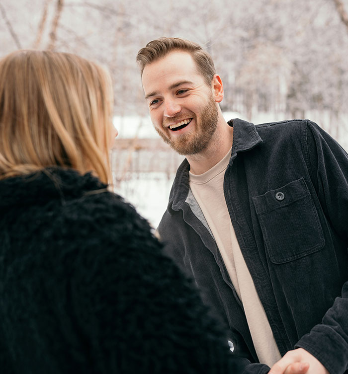 Dos personas conversando alegremente al aire libre en un día nevado.