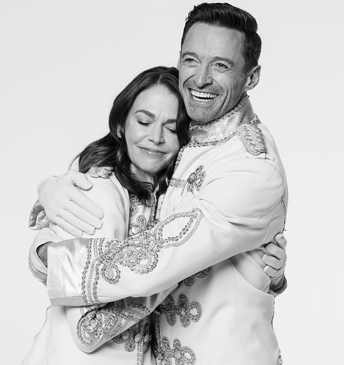 Two people smiling and hugging, wearing intricately embroidered costumes, exuding happiness and relief.