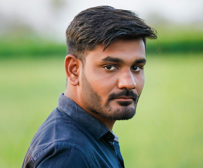 Man in a blue shirt standing in a field, contemplating an ultimatum about his wife's yoga teaching career.