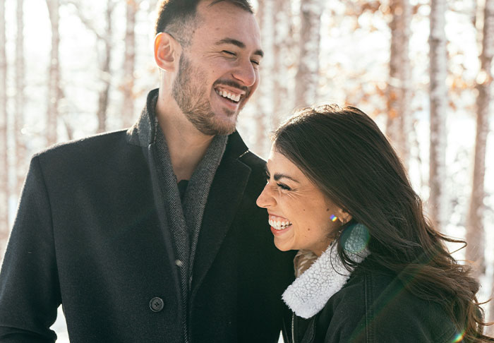 A joyful couple sharing a laugh in a snowy setting after receiving a life-changing gift.