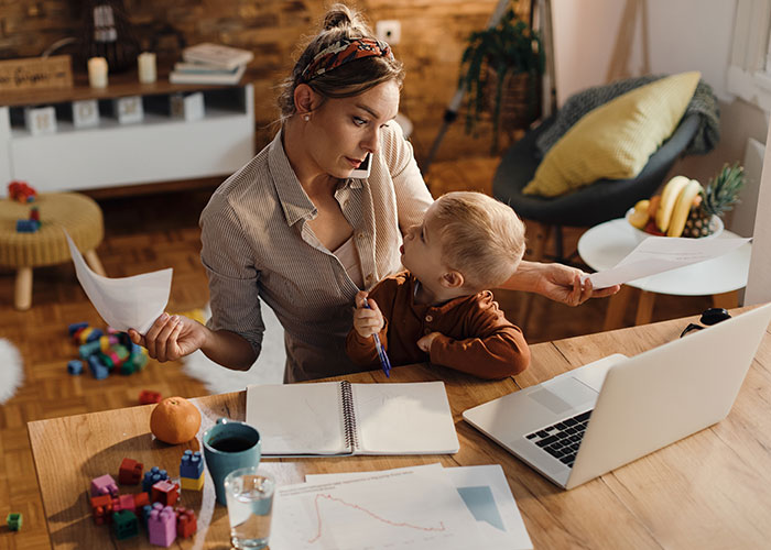 Woman balancing work and motherhood at a home office, representing challenges in marriage and job decisions.