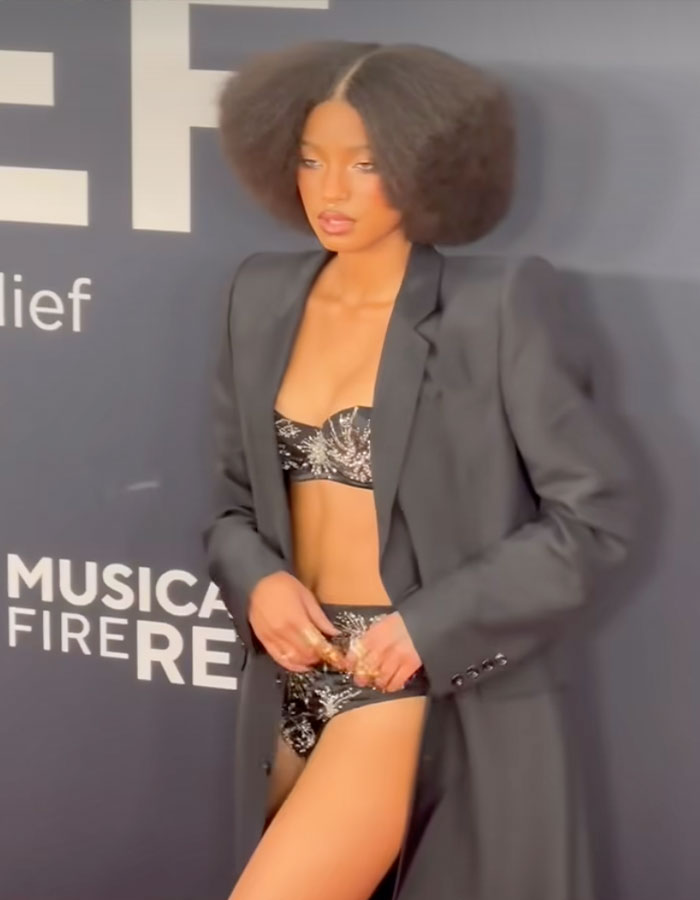 Young woman in a bold outfit with a black blazer and printed lingerie at the Grammys 2025.