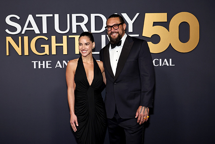 Jason Momoa and guest in formal attire at a red carpet event, posing together.