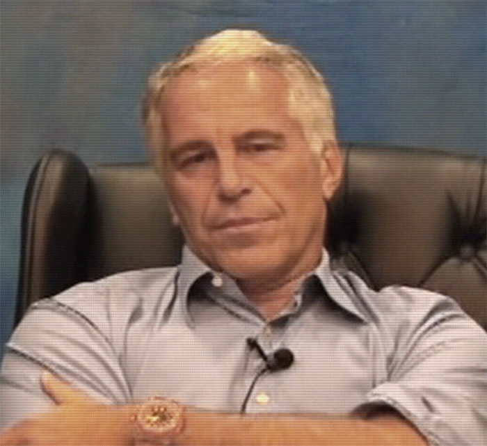 A man in a blue shirt sits in an office chair, associated with secret documents and celebrity names.