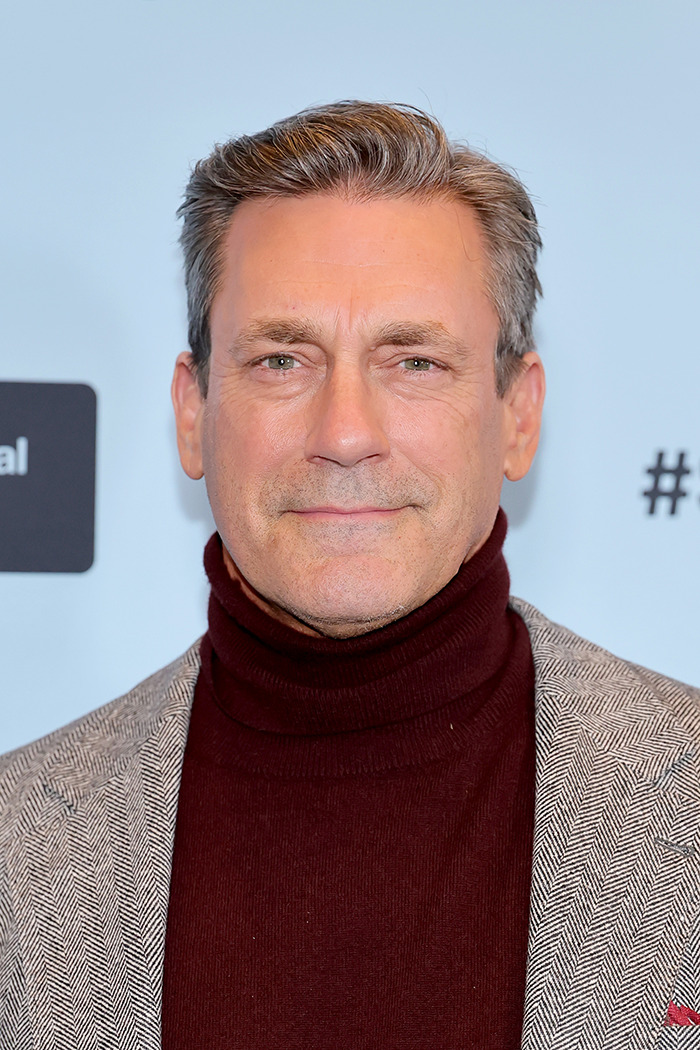 Man in a maroon turtleneck and gray blazer at a public event, related to Jon Hamm's controversial joke.