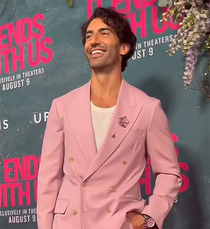 Man in a pink suit smiling at a movie premiere, related to 