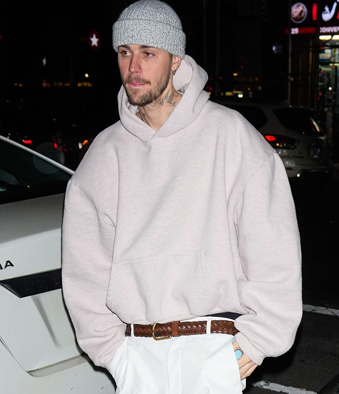 Man in a gray beanie and hoodie walking in a parking lot at night, related to discussions of substance abuse concerns.