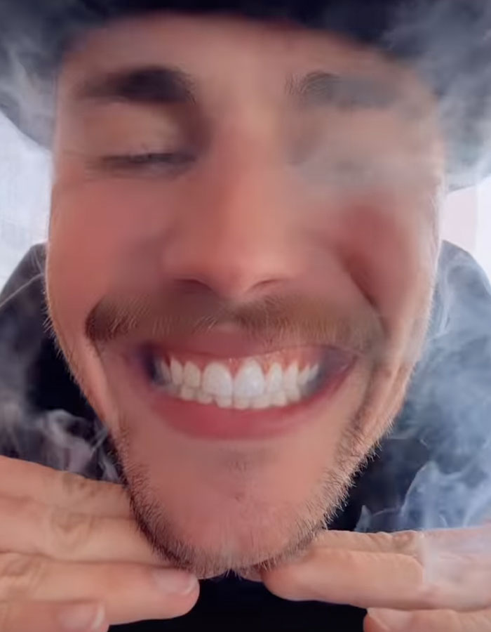 Person smiling with smoke surrounding their face, creating a hazy effect.