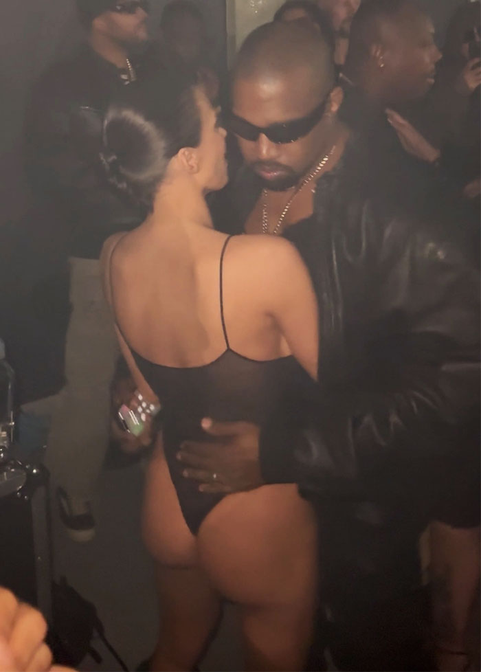 Two people embrace at a Grammys afterparty; one wears a revealing black outfit.