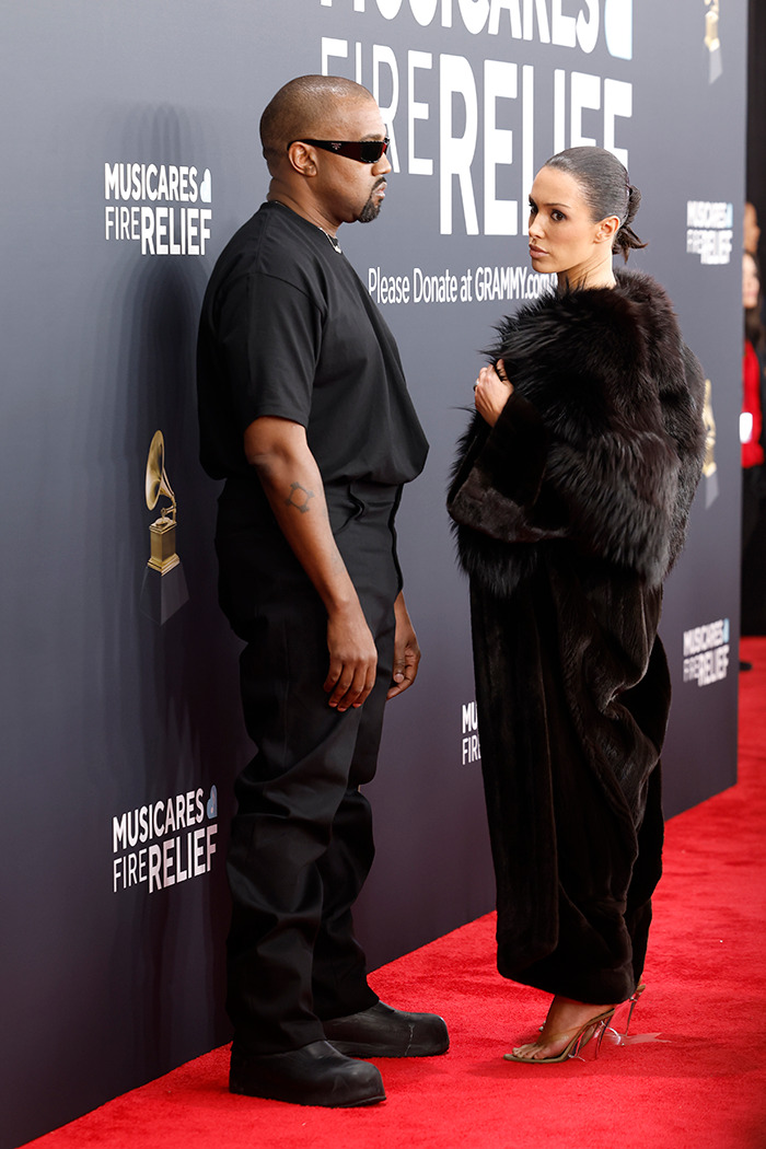 Kanye and Bianca on Grammys red carpet, Kanye in black outfit, Bianca in fur coat, standing in front of a MusiCares sign.