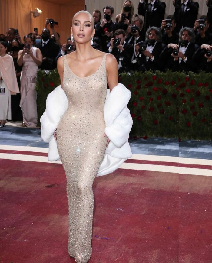 Kim Kardashian at the Met Gala wearing an ultra-tight corset gown, surrounded by photographers.