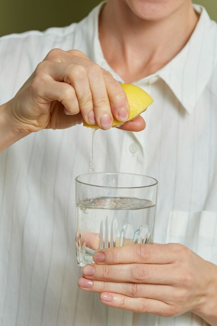 Person squeezing lemon into glass of water, demonstrating a fresh perspective on everyday activities.