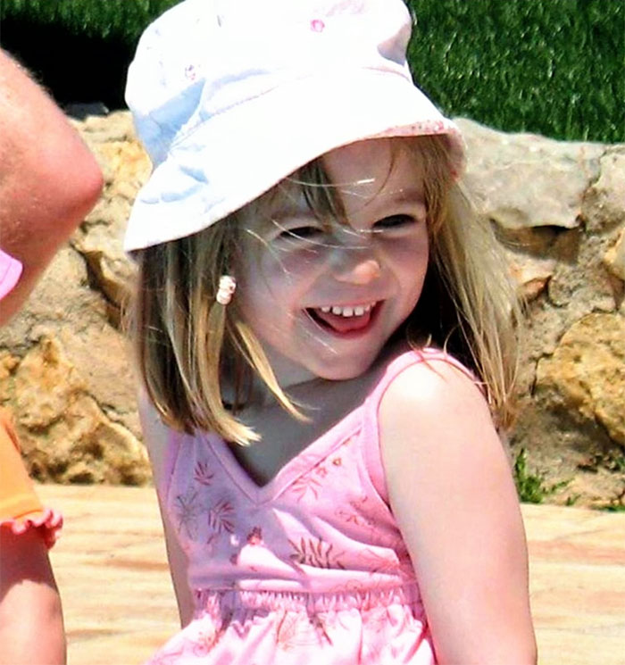 Young girl in a pink dress and hat, smiling outdoors.