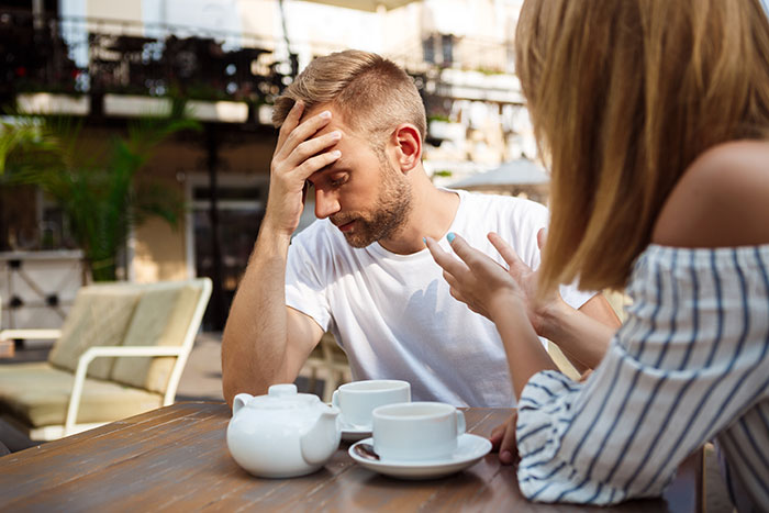 A couple at a cafe; woman talking, man looking stressed, ultimatum.