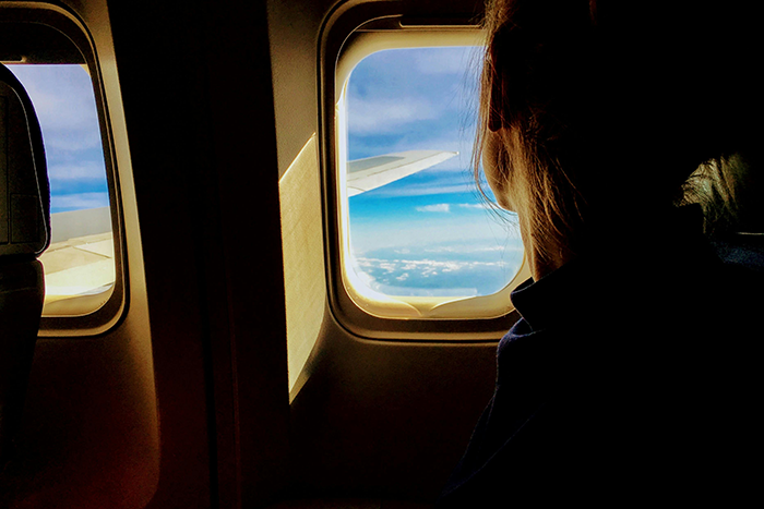 Person viewing clouds from an airplane seat through a window, highlighting the desire for a window seat.