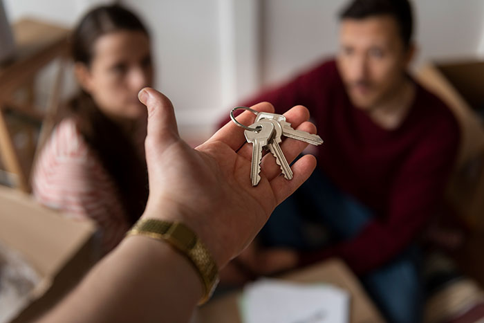 Keys being handed over to a young couple moving out.