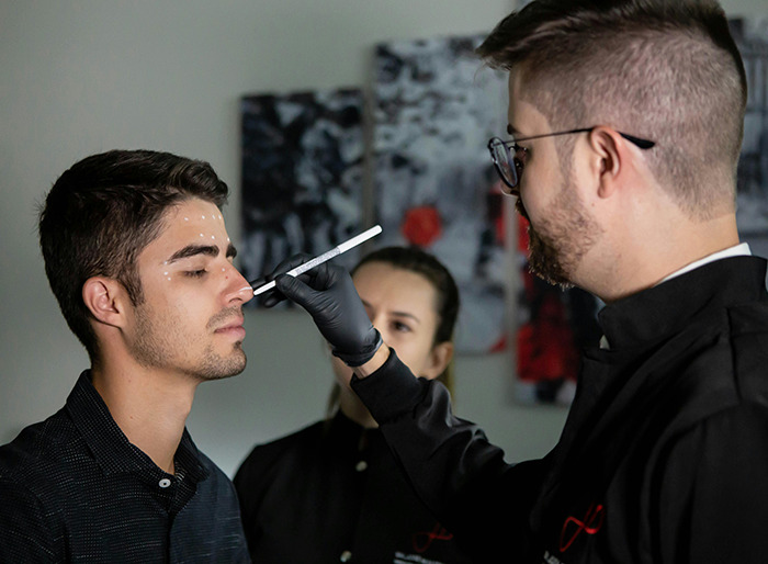 Man undergoing plastic surgery consultation, marking areas on his face with a professional, highlighting transformation potential.