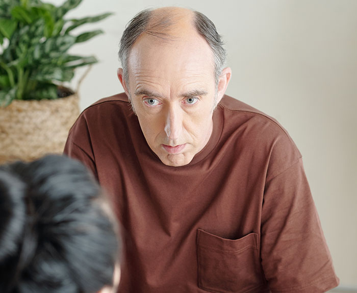 Man in brown shirt appears concerned, discussing issues related to stepdaughter's lies.