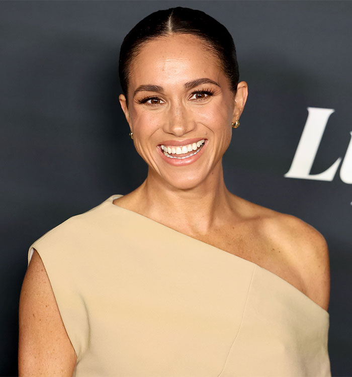 Woman in an elegant beige dress smiling on a red carpet, discussed for her kids' parties advice.