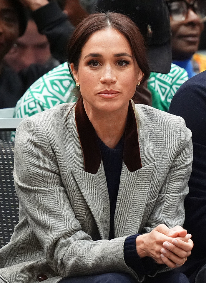 Woman in a grey blazer seated, amid controversy over rebranding and logo accusation.