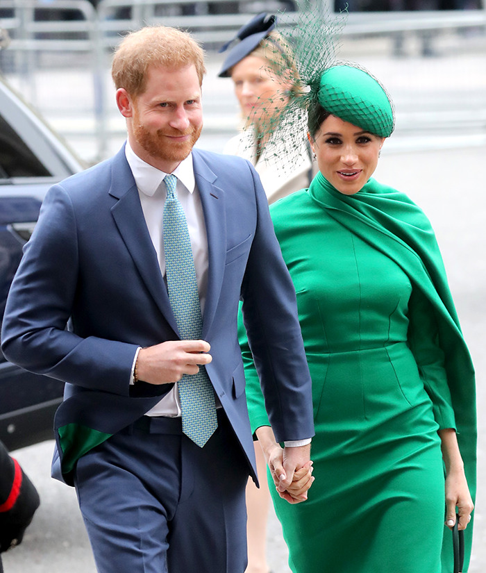 Meghan Markle and Prince Harry walking outdoors while holding hands.