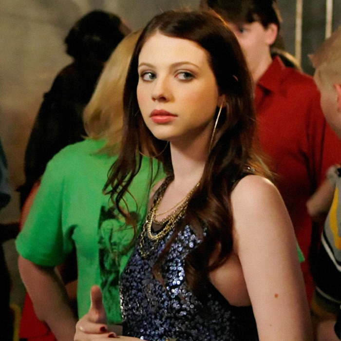 Michelle Trachtenberg in a sparkly dress at a social gathering, turning towards the camera.