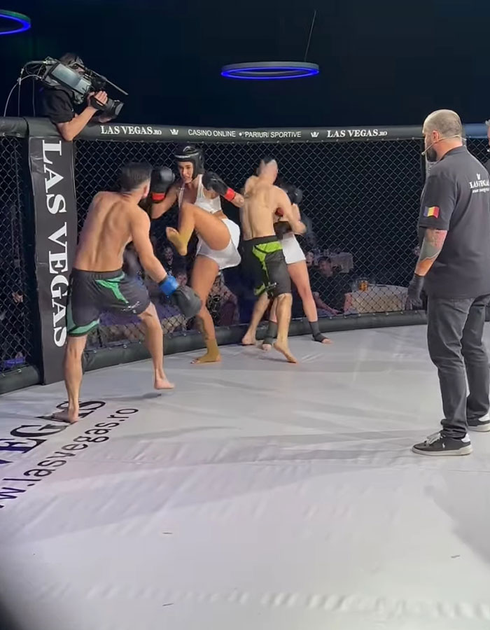 Controversial MMA fight with two pro men and three women in a ring, surrounded by a referee and cameraman.