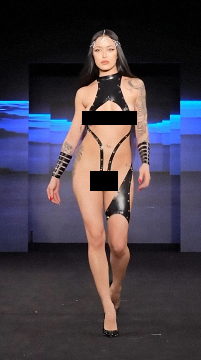 Model at New York Fashion Week wearing creative tape attire on the runway.