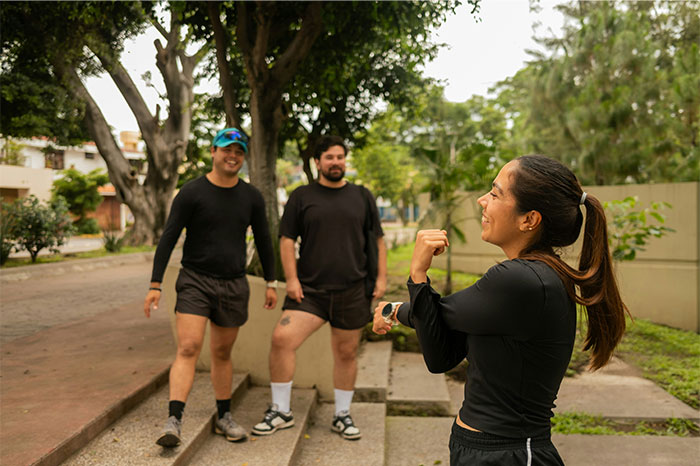 Group of adults enjoying trail running outside on a sunny day, smiling and dressed in athletic wear.