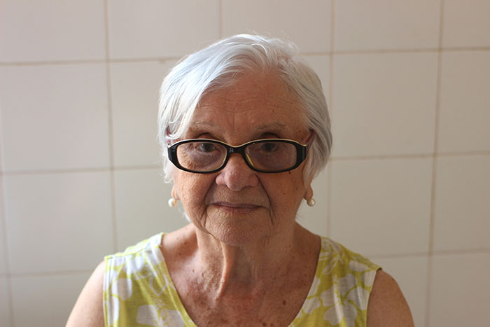 Elderly woman with glasses and a patterned blouse, related to a story about a mother-in-law offended over sleeping arrangements.