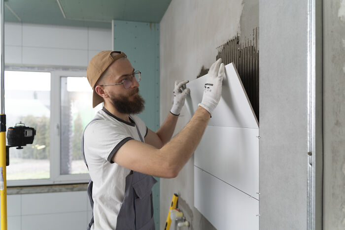 Man installing tiles in a new house, balancing job and move with family challenges.