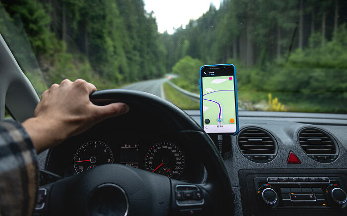 Driving with a GPS app on a smartphone, essential travel must-have for road trips.