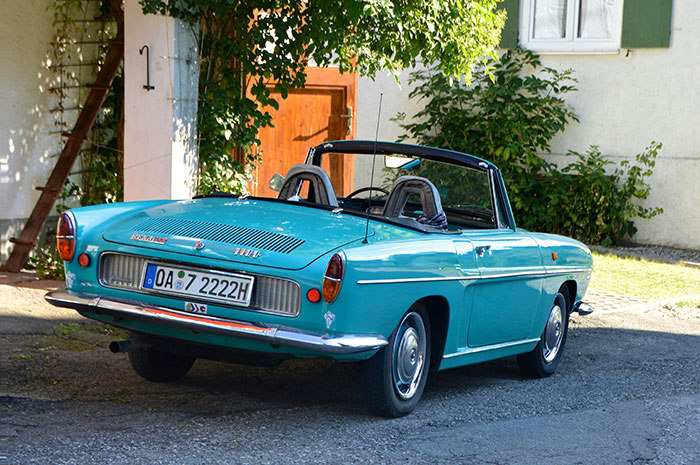 A vintage convertible car parked near a neighbor\'s driveway without authorization.