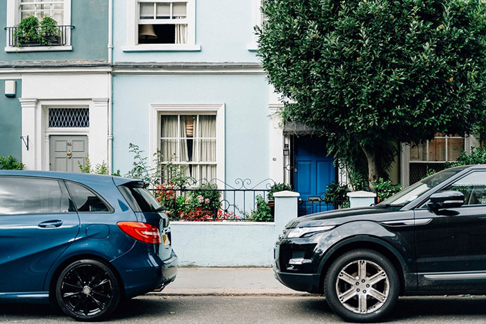 Unauthorized car parking by a neighbor in front of a blue house.