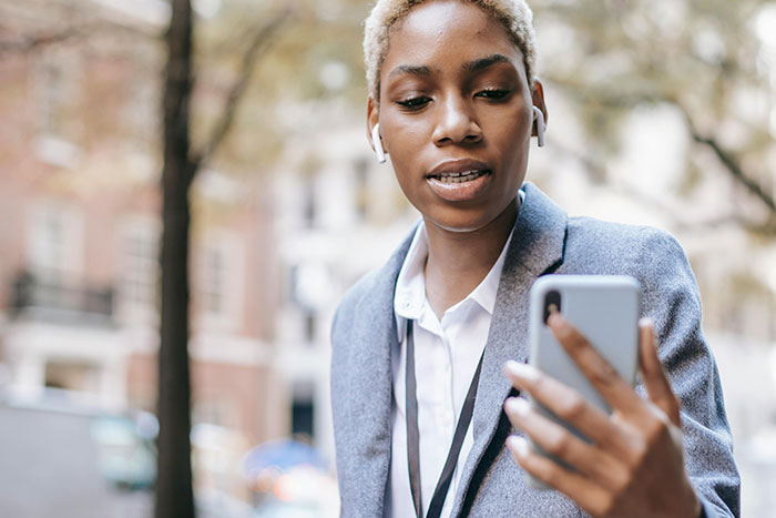 Person in a blazer looking at a phone outdoors, possibly addressing a neighbor parking car unauthorized issue.