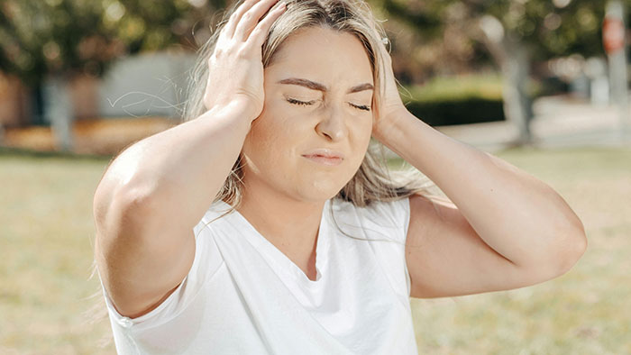 Woman outdoors looking frustrated over unauthorized car parking by neighbor.