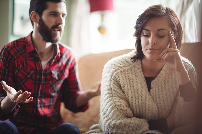 Man in plaid shirt discussing unauthorized parking while woman in a sweater appears frustrated at home.