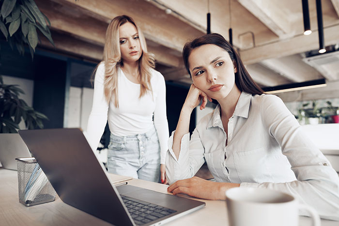 Woman seeking advice at work, visibly concerned after a colleague's threat regarding the graveyard shift.