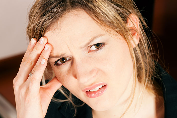 A concerned woman touching her forehead, illustrating tension in a conversation about bonding with stepchildren.