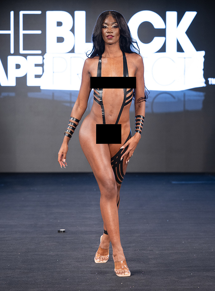 Model at New York Fashion Week wearing tape design on runway.