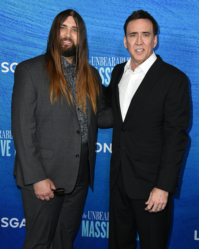 Two men in suits at a blue-themed event, posing for a photo.