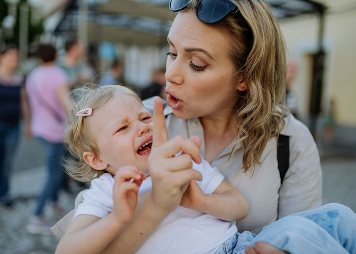 Parenting coach explaining to upset child while pointing a finger, emphasizing calm communication over yelling.