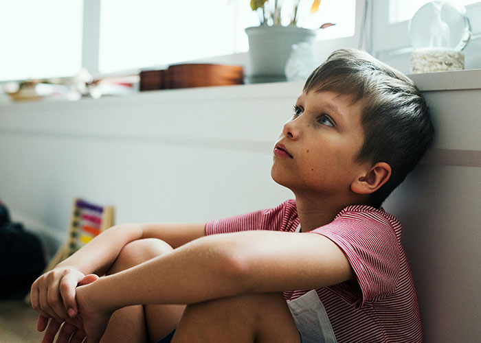 Child sitting thoughtfully in a sunlit room, highlighting parenting coach advice on stopping yelling at kids.