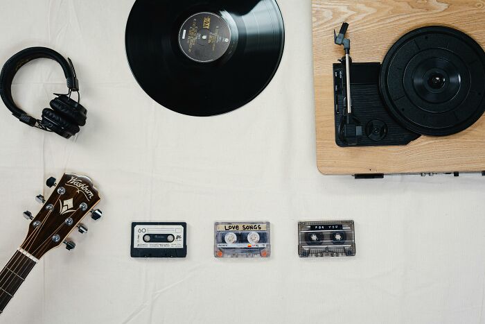 Vinyl record, cassette tapes, headphones, and guitar on display; explore your guilty pleasure in music.