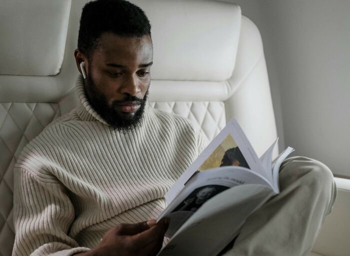 Man on a plane reading a magazine, representing travel must-haves for efficient packing.