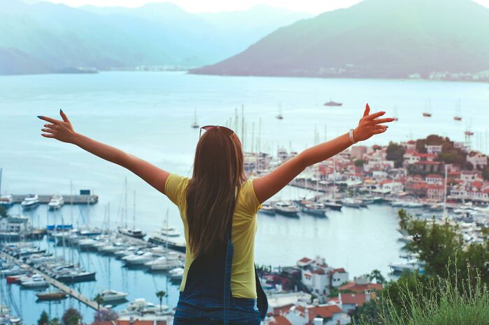 Woman enjoying a scenic view of a marina and mountains, embracing the childfree life and its lifestyle benefits.