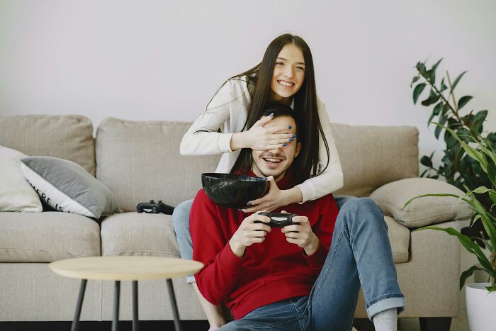 Childfree couple enjoying a video game, sitting on a cozy sofa with a playful atmosphere.