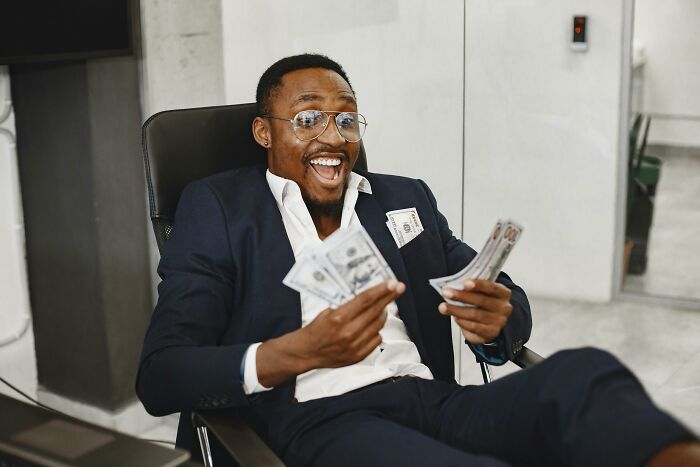 Man in a suit smiling and holding cash, representing the benefits of being childfree.